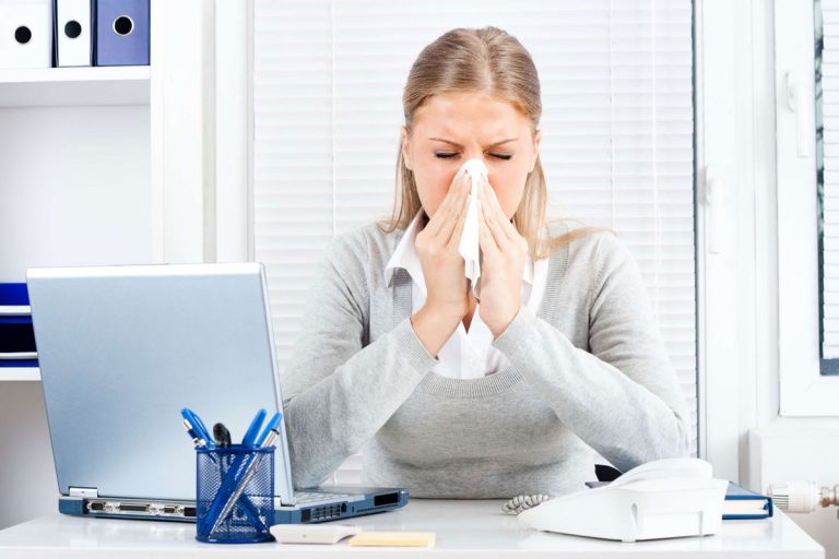 Woman in an office blowing her nose
